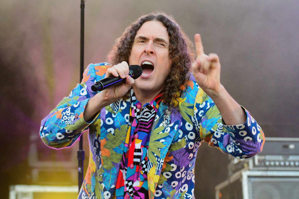 Weird Al Yankovic smiling during live performance, related to weird al yankovic net worth